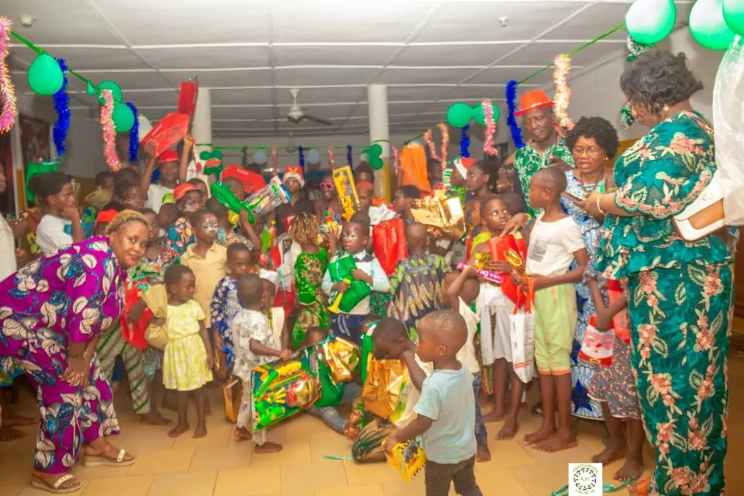Tout joyeux, les enfants tiennent jalousement leurs cadeaux en compagnie des donateurs